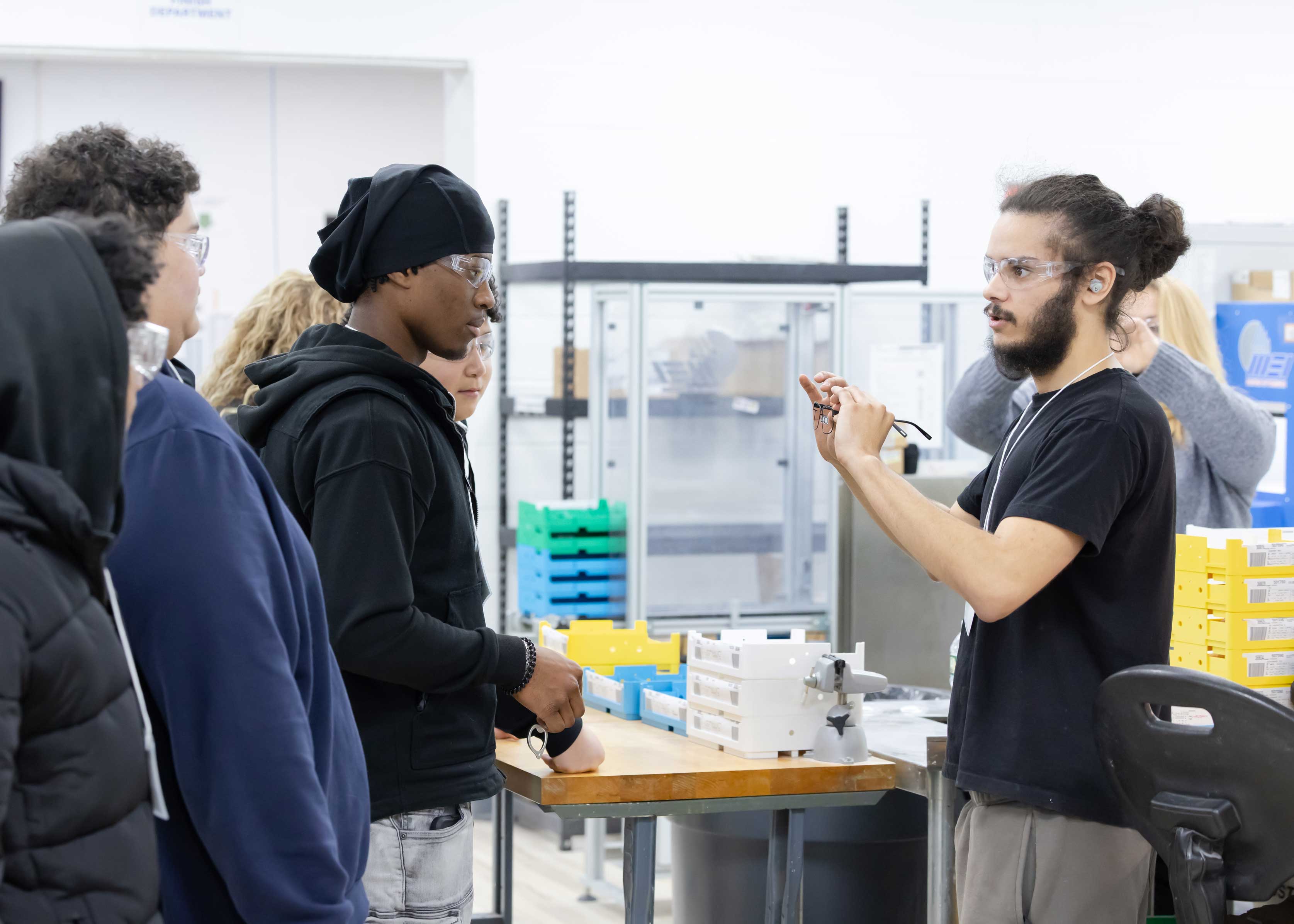 Group of people in a workshop setting with one person demonstrating something.