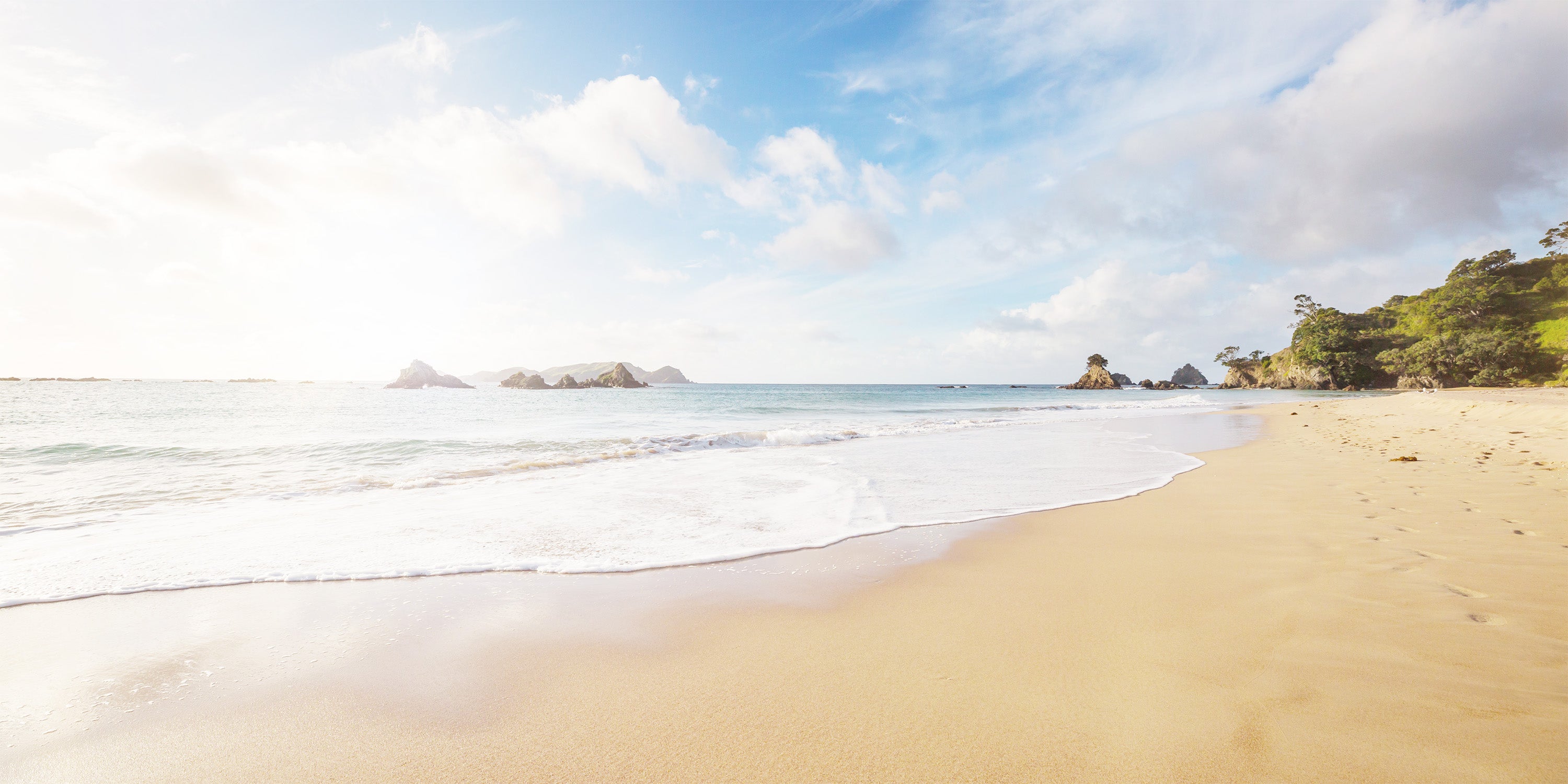 Beach scene with clear blue sky and ocean waves.