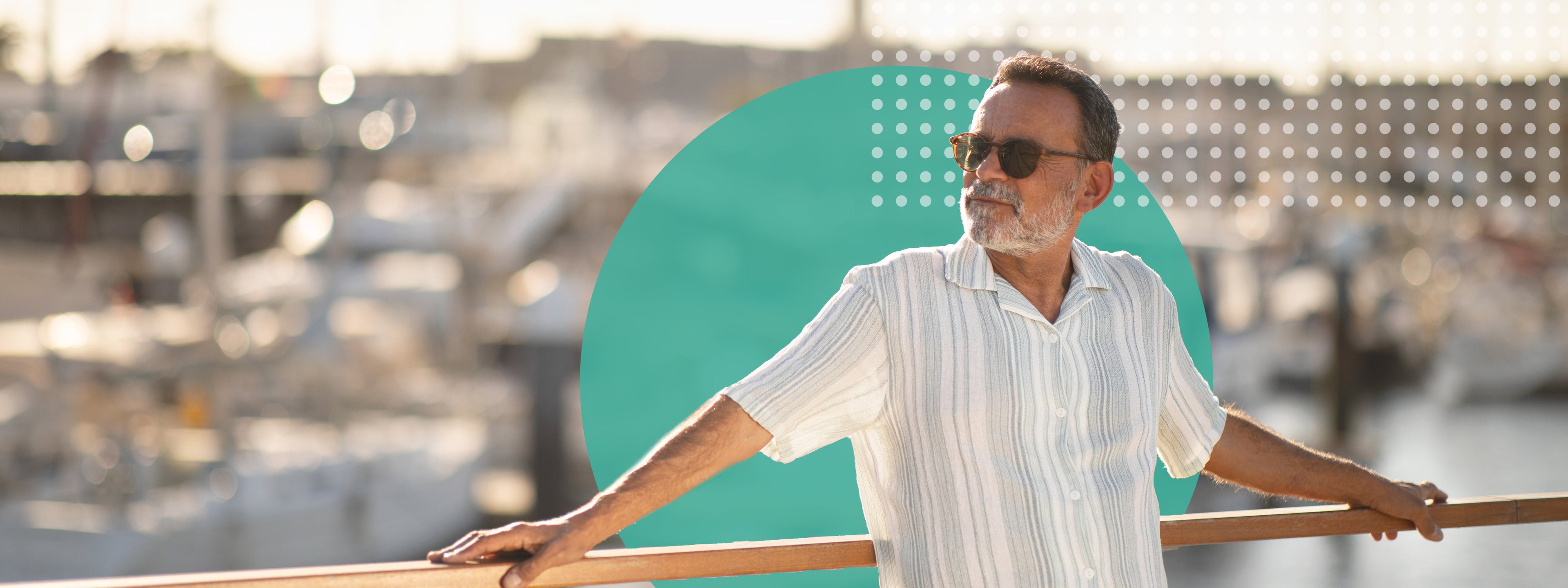 Man in sunglasses and a white shirt standing on a dock with boats in the background