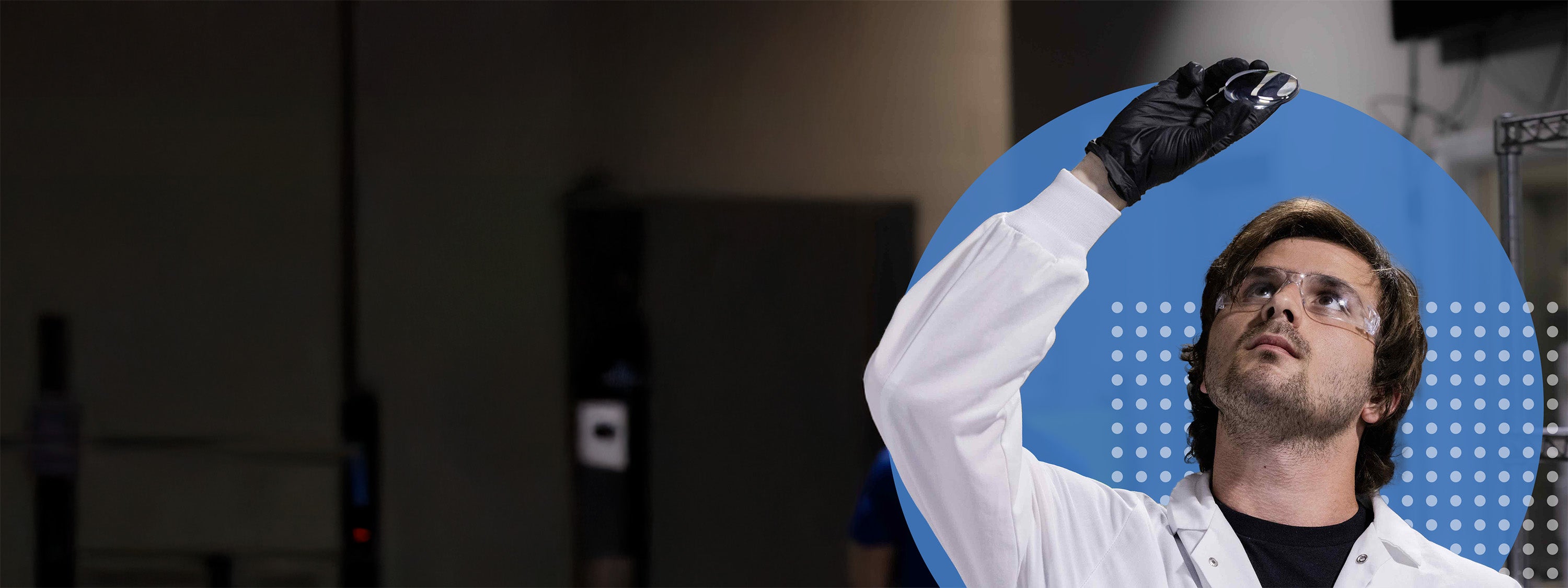 Person wearing a white lab coat and black gloves against a blue circular background