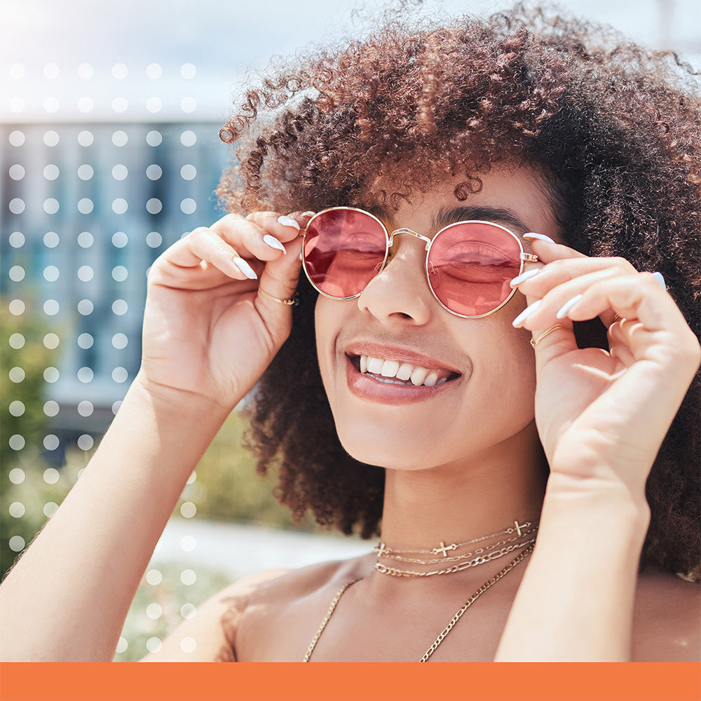 Woman wearing pink sunglasses with a blurred outdoor background