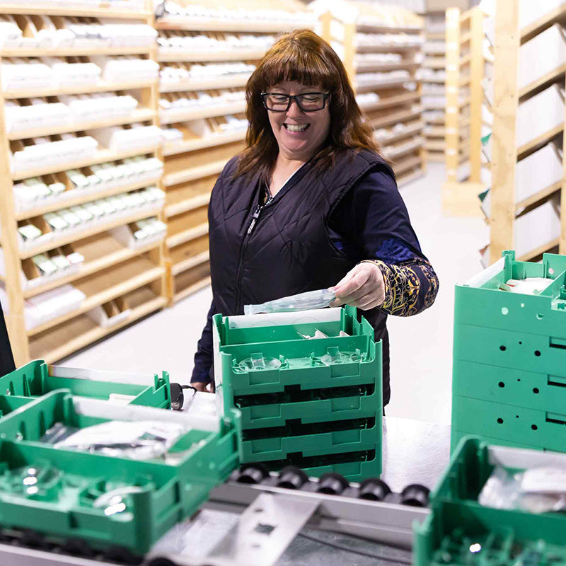 Person organizing green crates in a storage area with shelves in the background