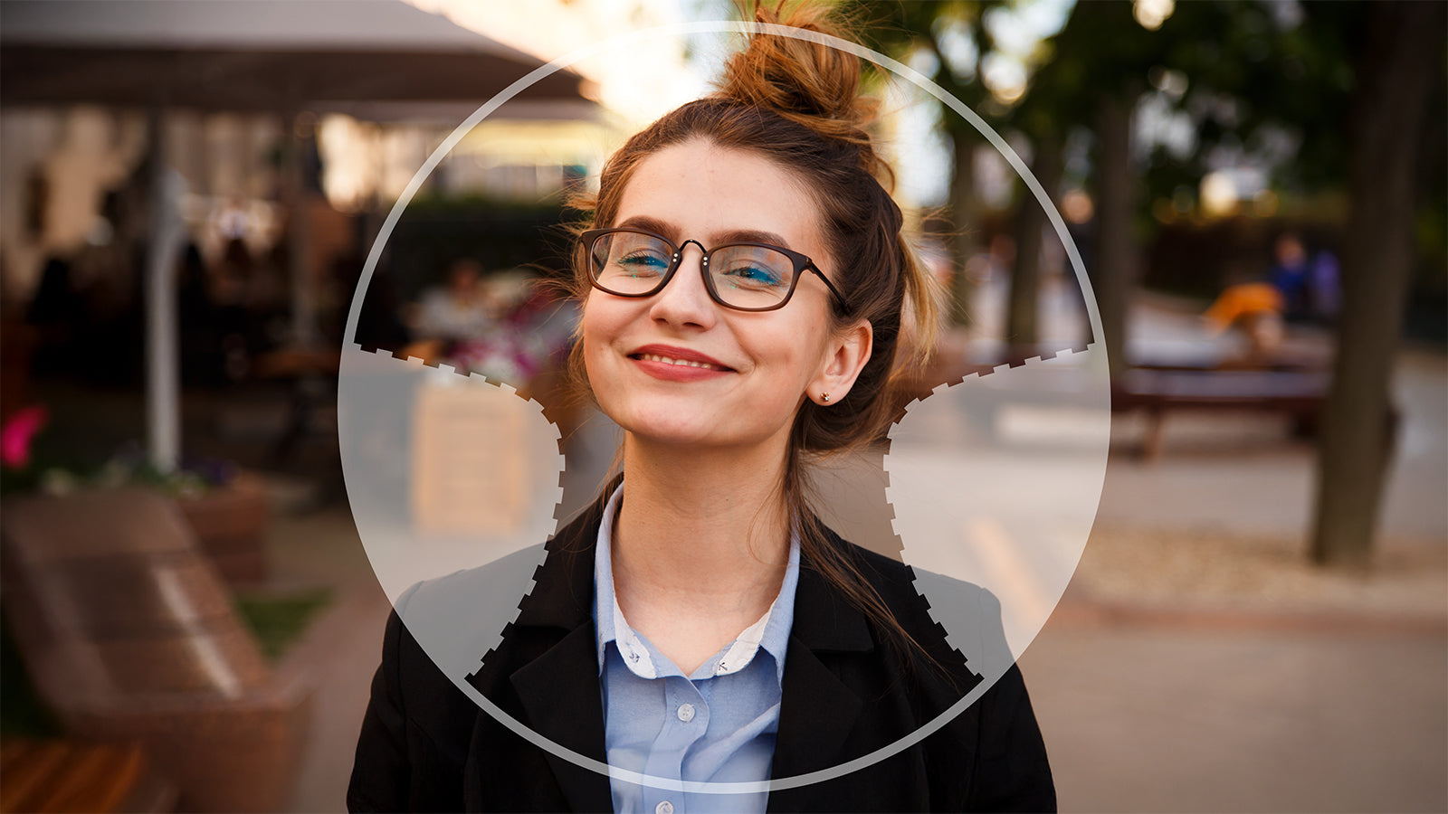 Woman with glasses smiling outdoors in a blurred background