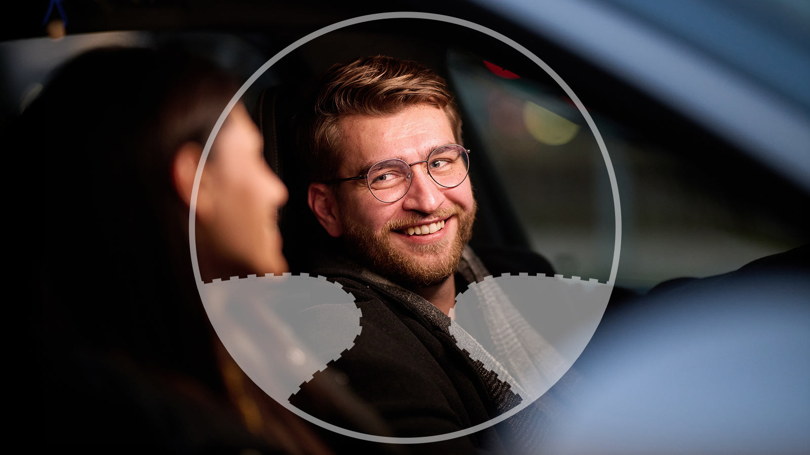 Man with glasses smiling through a car window