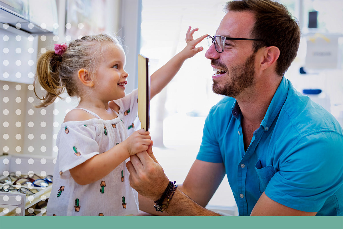 Man and young girl in a kitchen setting, with the man holding a pair of glasses.